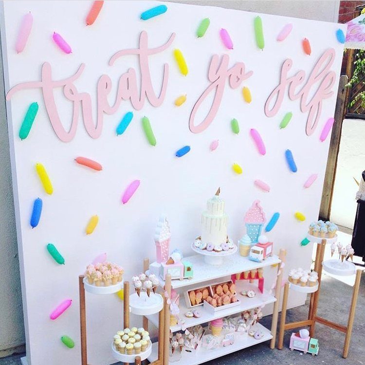 Dessert table with ice cream treats and sprinkle decorations on a white wall