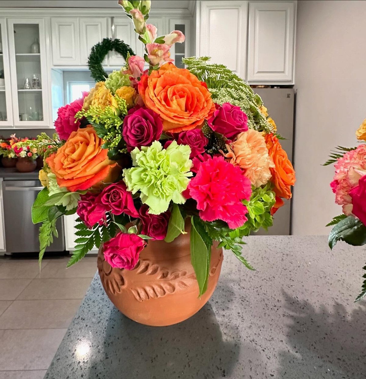 Colorful floral arrangement in a terracotta pot on a grey granite kitchen counter.