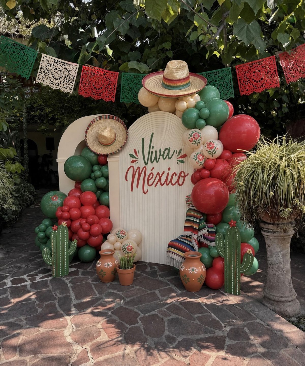 Festive Mexican party backdrop with red, white, and green balloons and sombreros.
