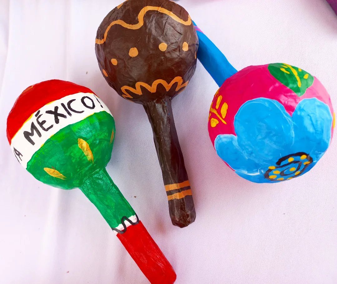 Three colorful handmade maracas with Mexican flag and floral designs on white background
