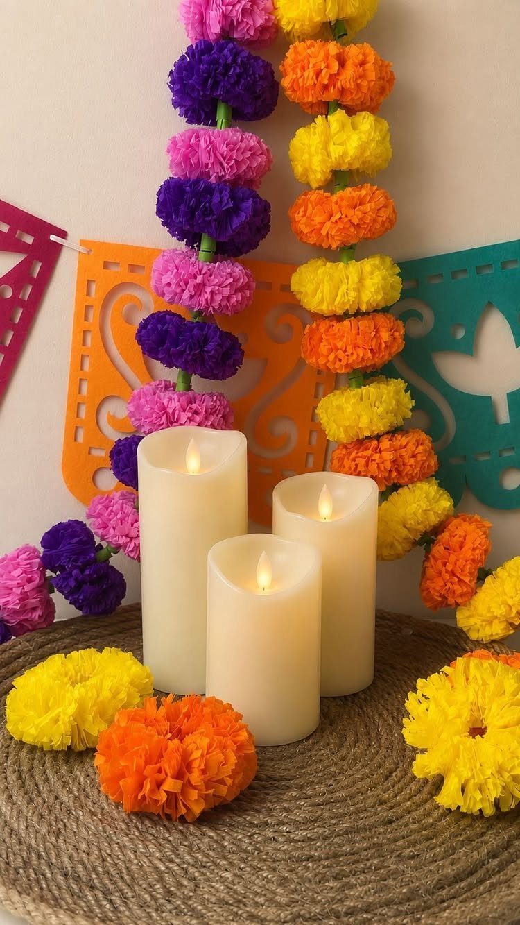 White pillar candles surrounded by colorful paper flowers and floral garlands on burlap.