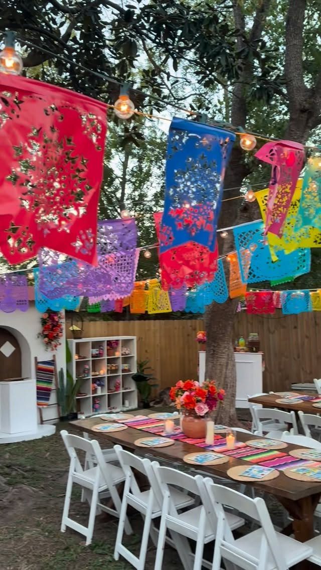 Wooden party table with a colorful striped serape runner and papel picado banners.