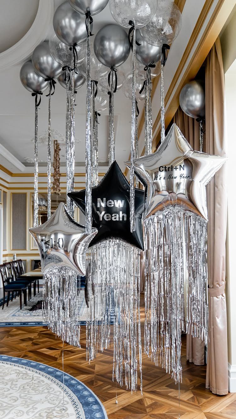 Silver and black balloons with hanging tinsel fringes in a bright room.