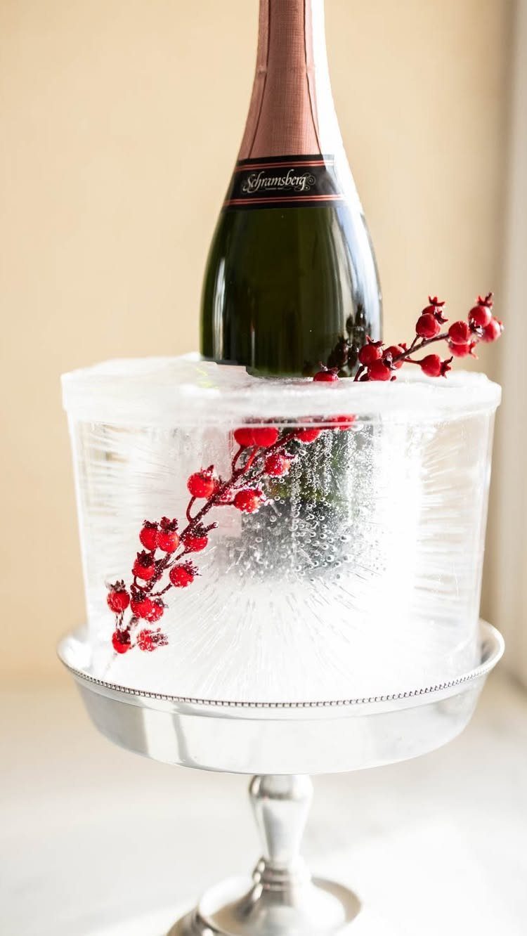 Champagne bottle chilled in a block of ice with red berries on silver stand