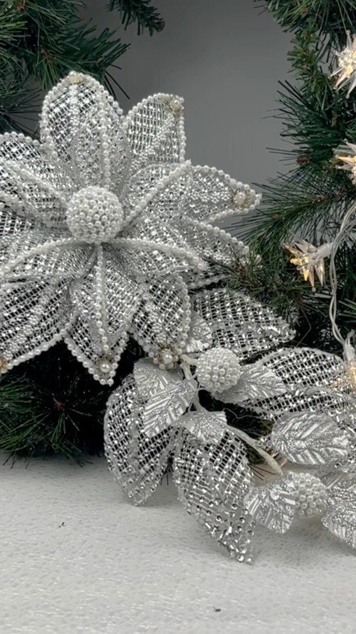 Silver glittery floral ornaments and beaded leaves tucked into a green pine wreath.