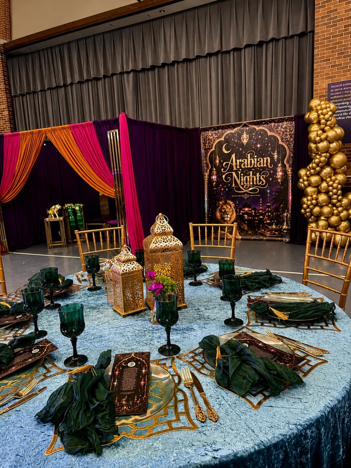 Event table with gold lanterns and green glassware before an Arabian Nights backdrop.