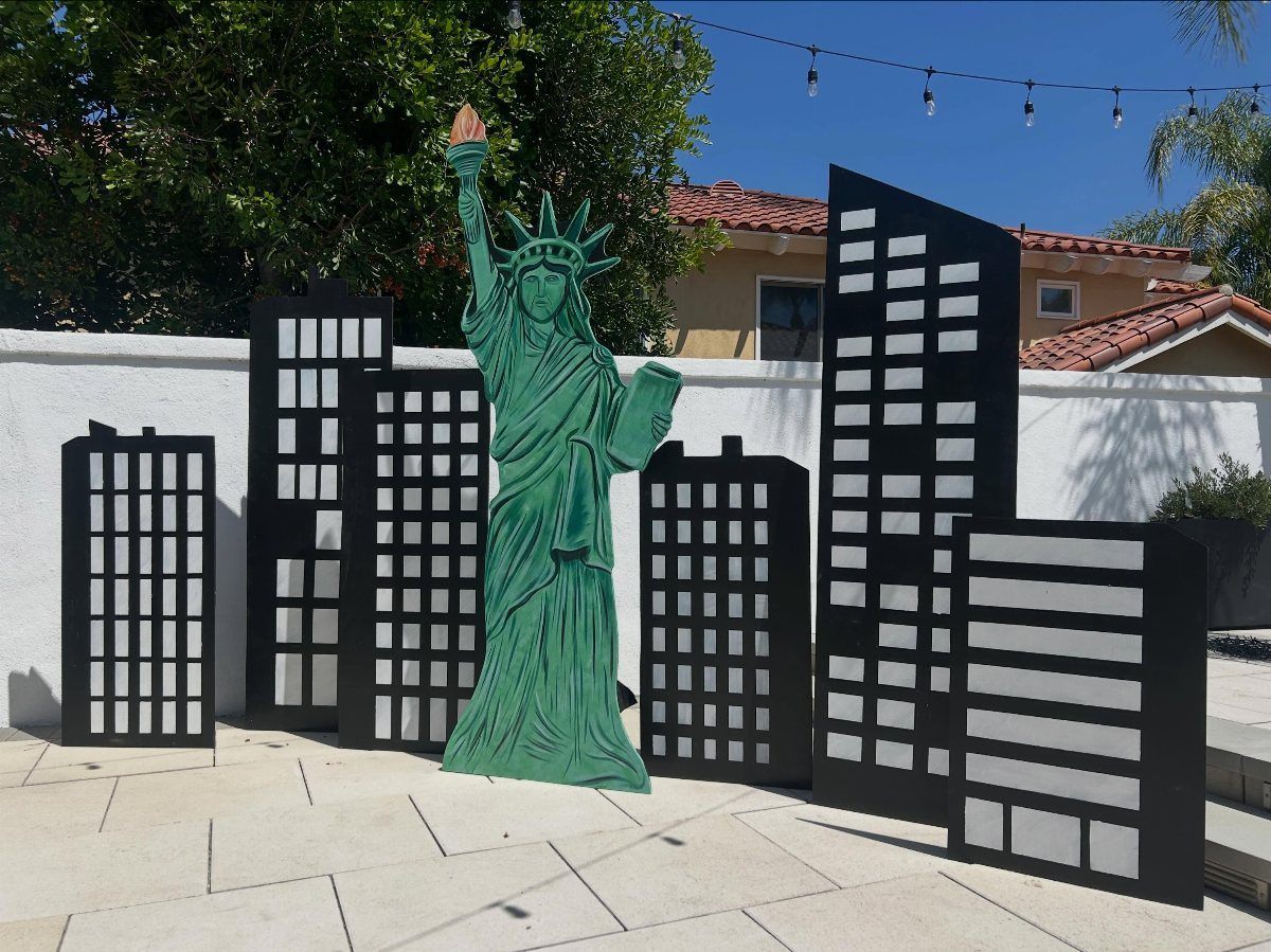 Statue of Liberty cutout standing before black city skyline silhouette decorations on a patio
