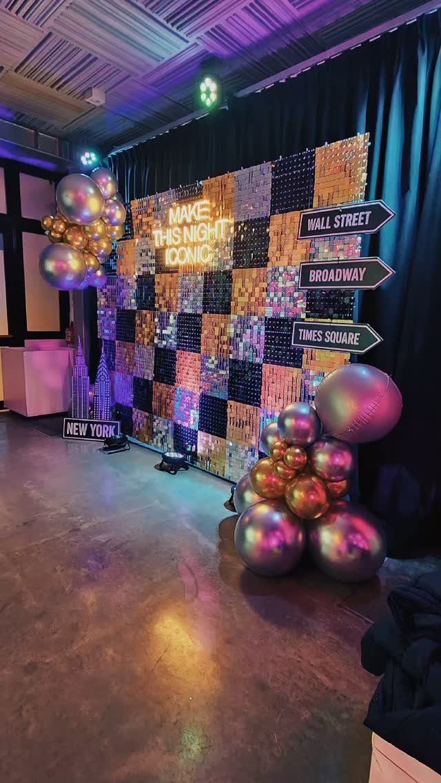 New York themed party backdrop with sequin wall, street signs, and metallic balloons.