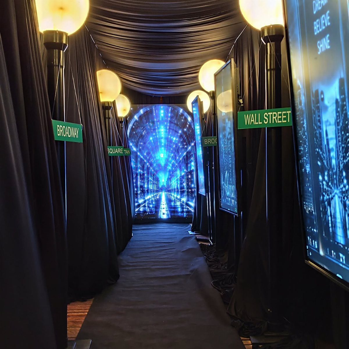 New York themed party entrance with black drapes, street signs, and digital screens.