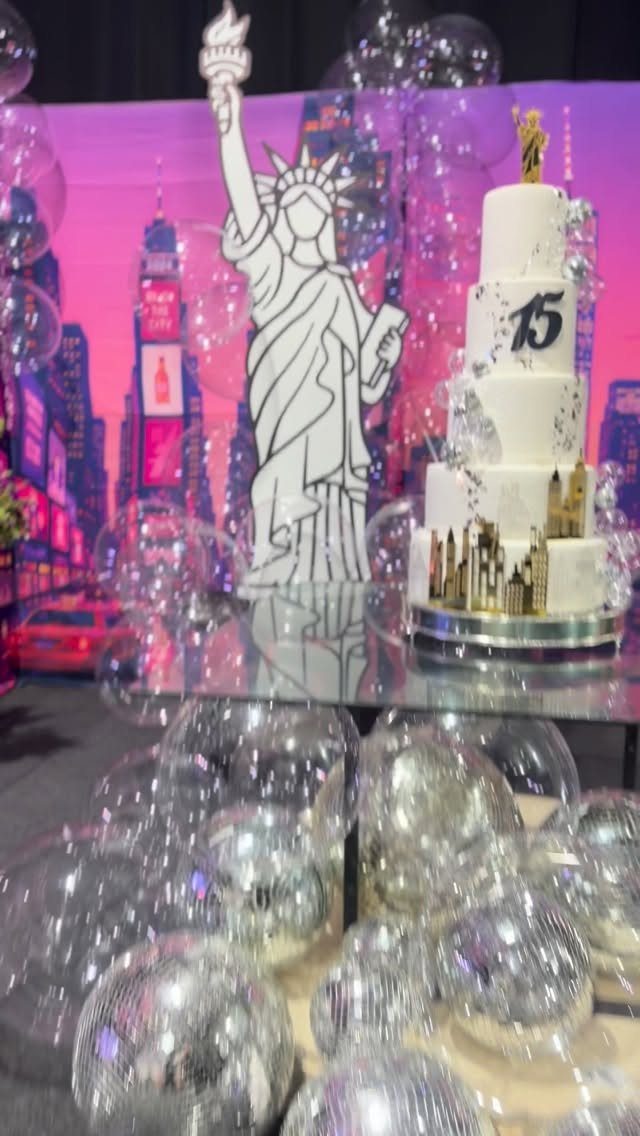 New York themed party decorations with a tiered cake and Statue of Liberty cutout.
