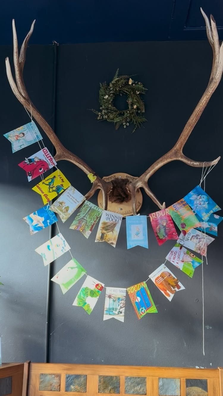Book page bunting banner strung across large deer antlers on a dark wall.