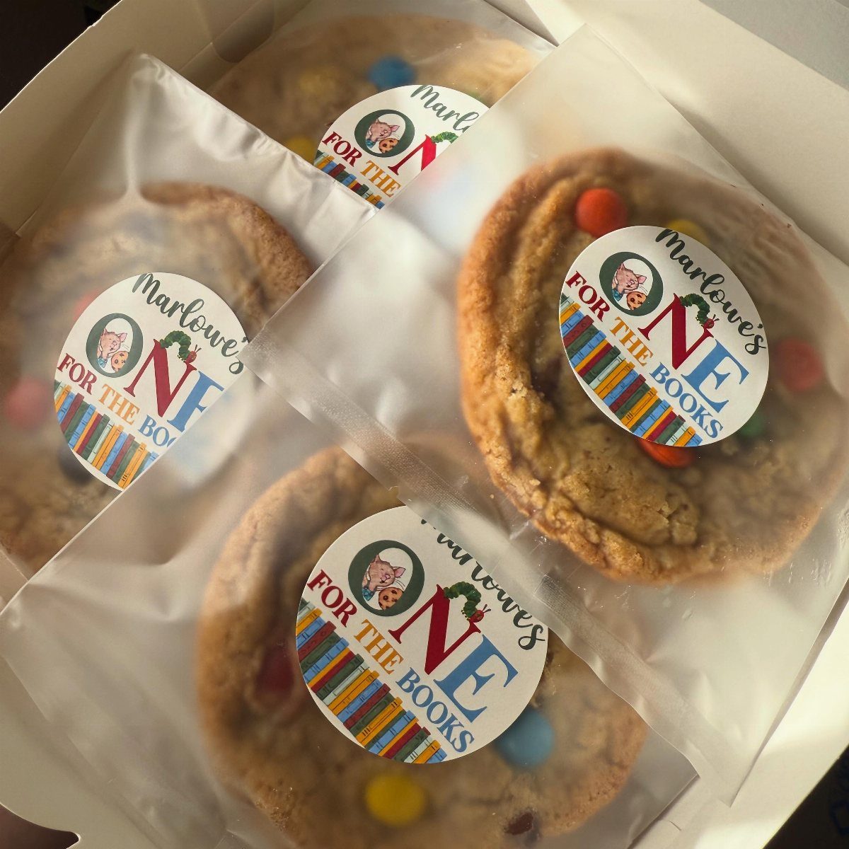 Wrapped chocolate chip cookies with book-themed birthday stickers in a white box.