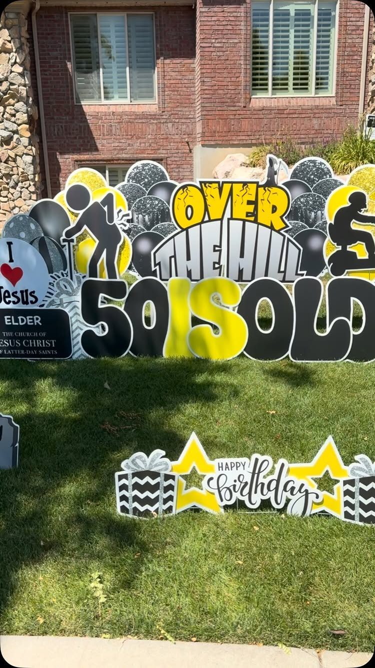 Black and yellow over the hill birthday yard signs on a green lawn.