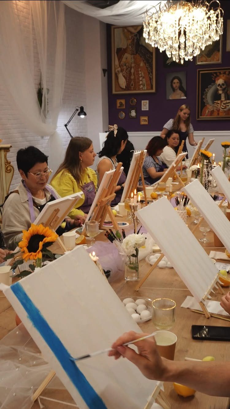Adults painting on canvases at a decorated table during a themed party event