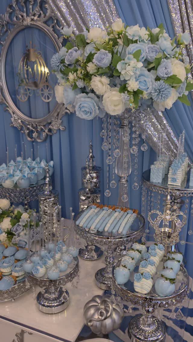 Blue and white dessert table with floral arrangements and silver stands for winter party.