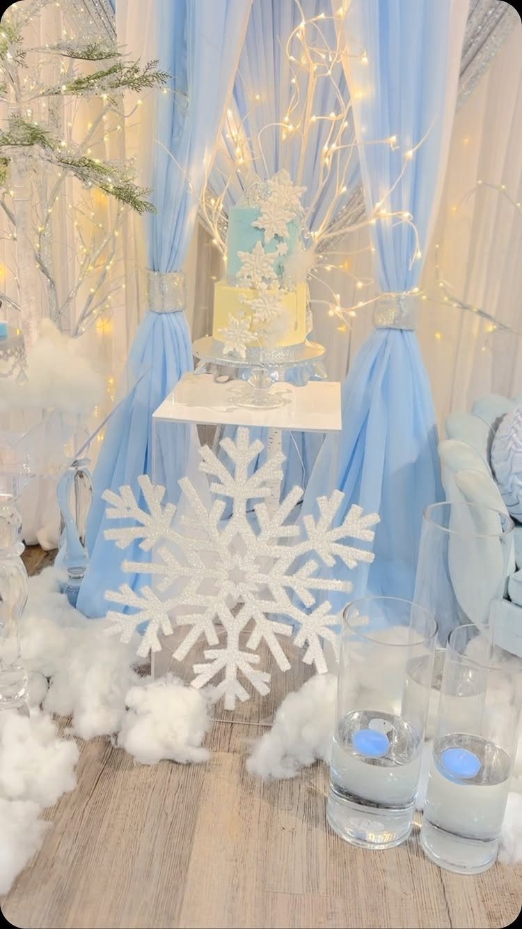 Winter Wonderland party setup with a blue cake, large snowflakes, and fairy lights.
