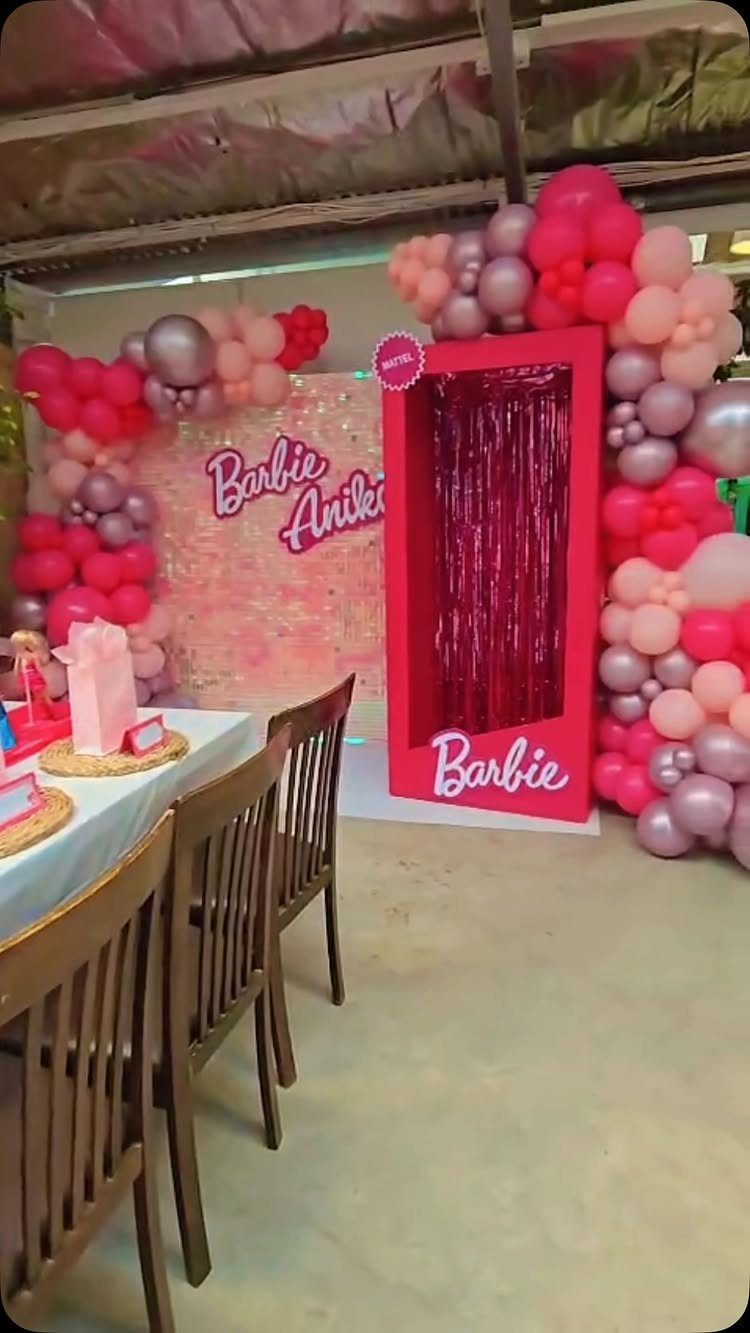 Barbie themed party setup with pink balloons and a pink photo booth entrance