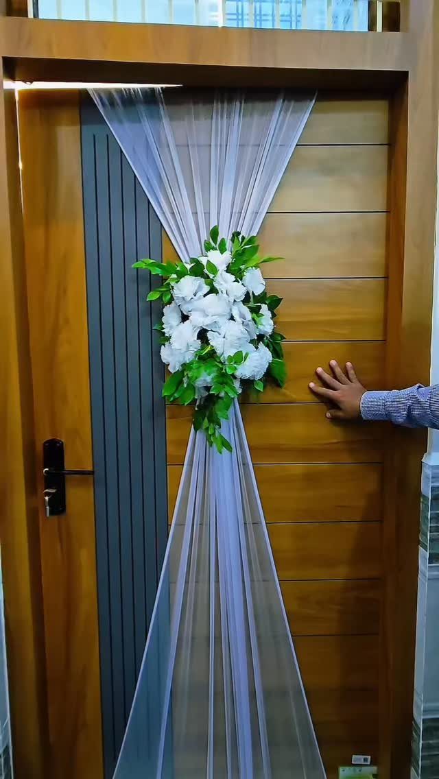 Wooden door decorated with white sheer fabric and a white floral bouquet.