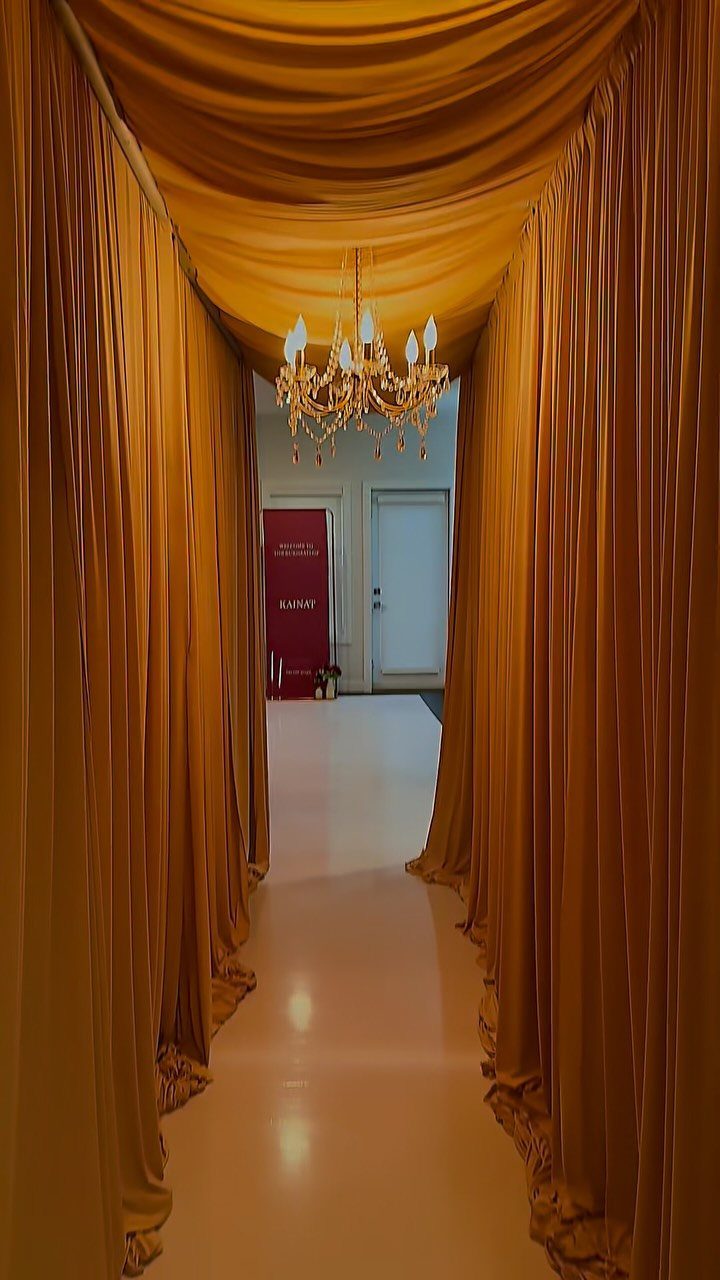 Gold fabric draping a hallway with a crystal chandelier hanging from the ceiling