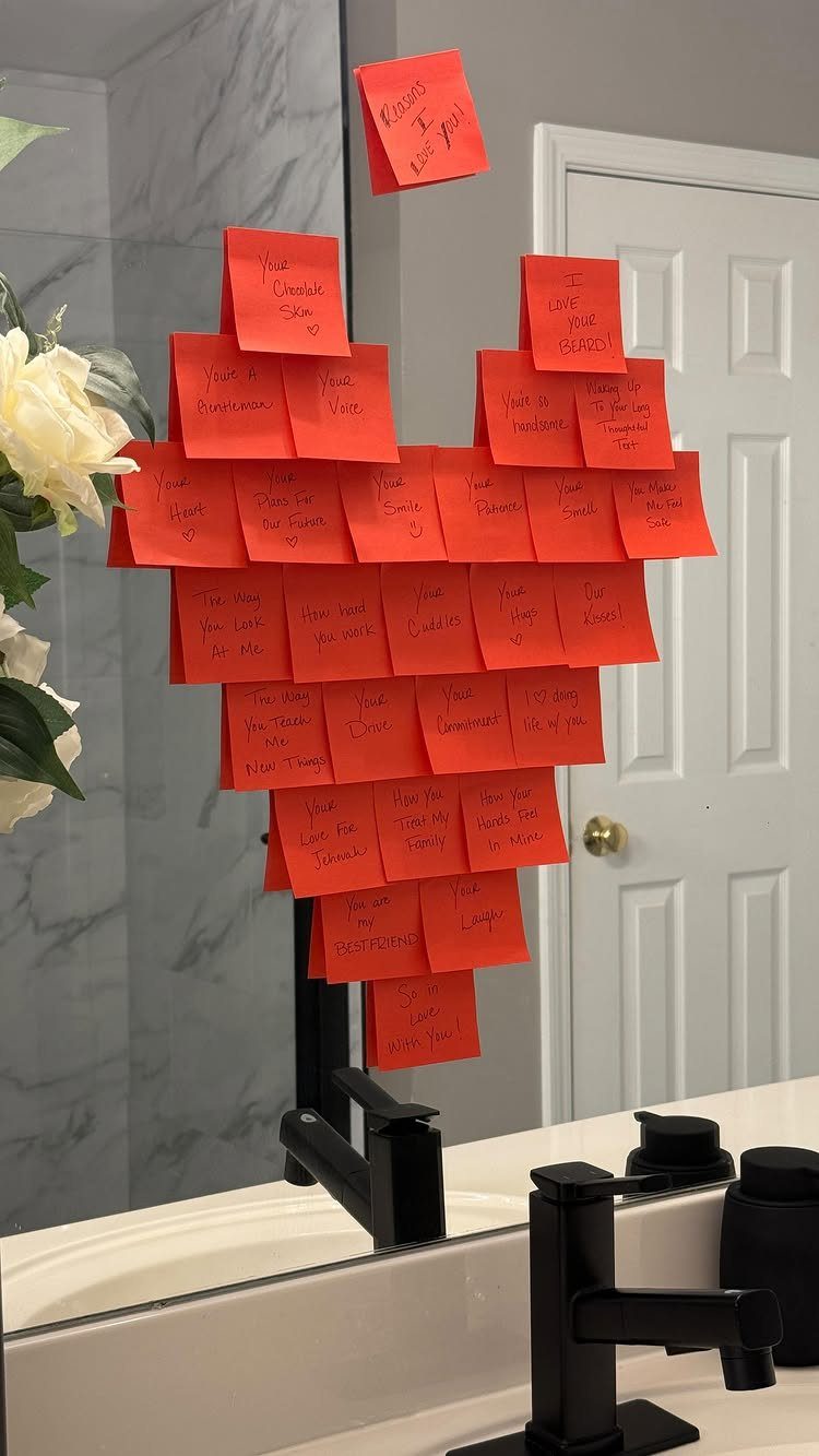 Red sticky notes arranged in a heart shape on a bathroom counter.