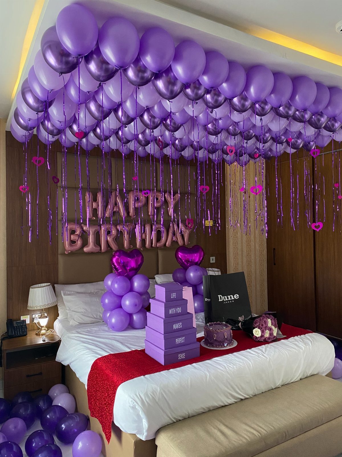 Purple balloons covering the ceiling and bed in a decorated birthday bedroom