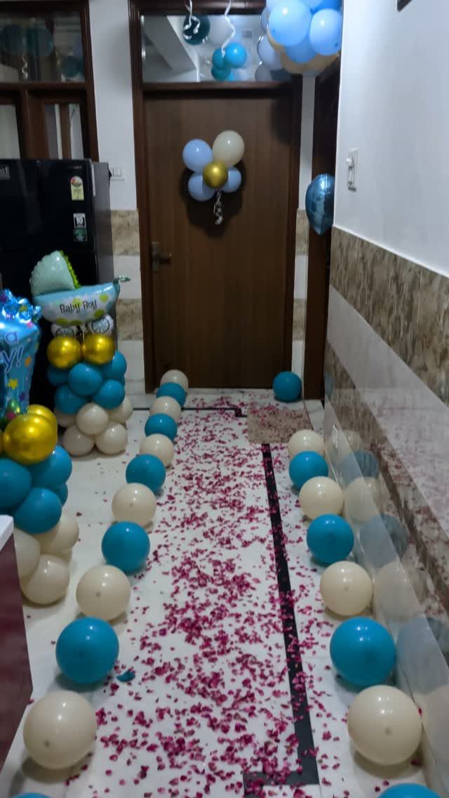 Blue and white balloons lining a hallway floor covered in pink petals.