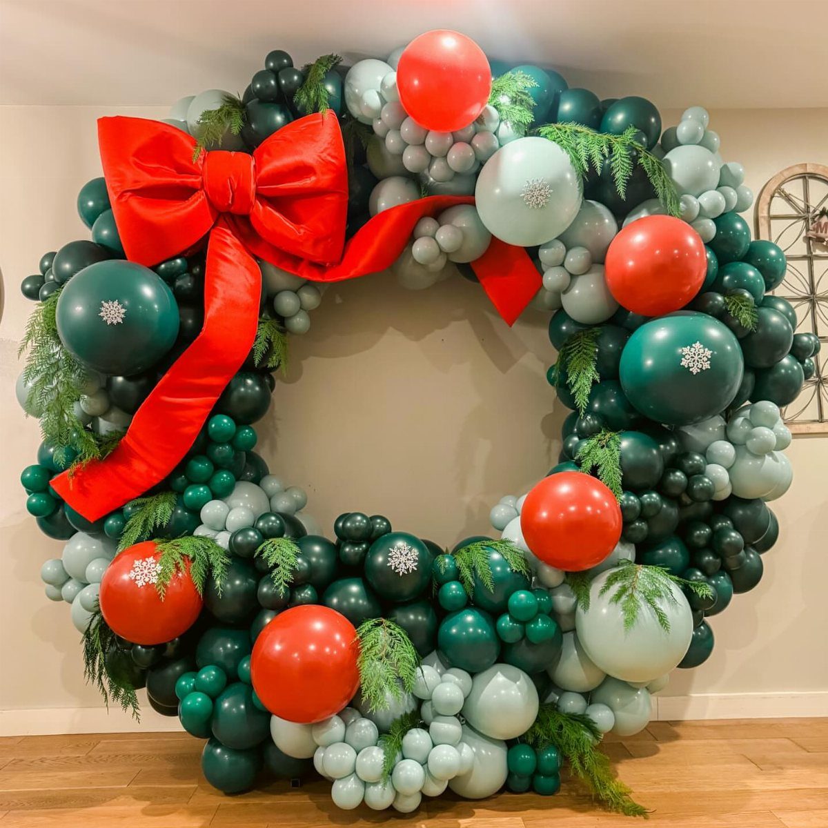 Circular balloon wreath in red and green with a large red bow.