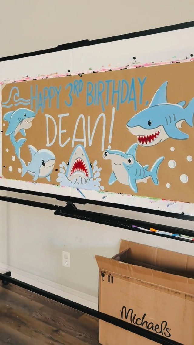 Shark themed birthday banner for Dean with blue cartoon sharks on brown paper.