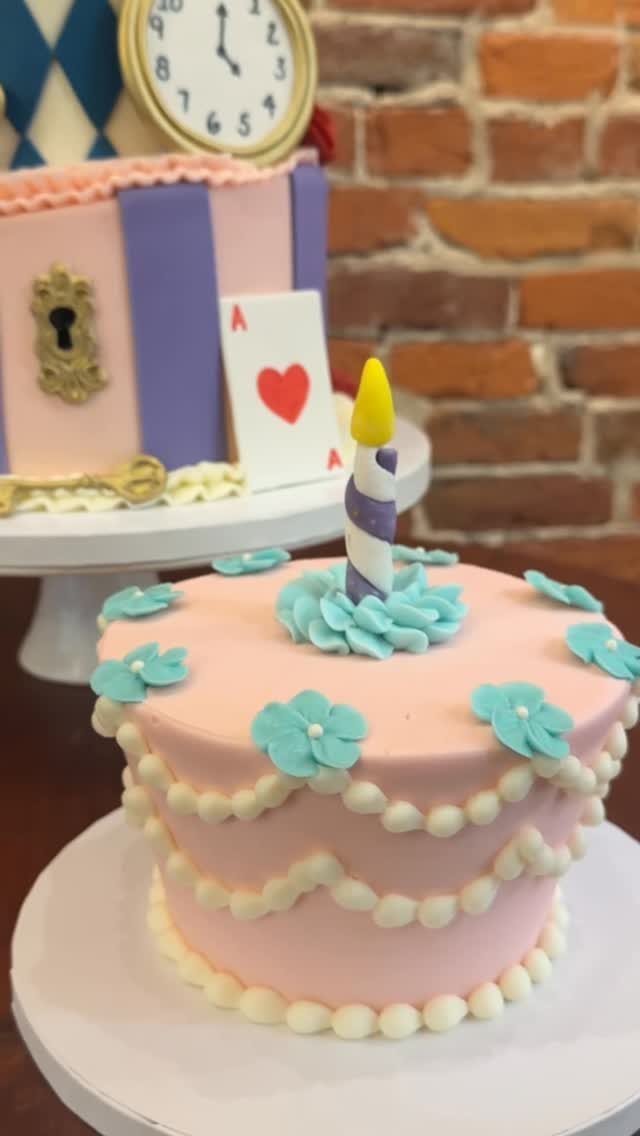 Pink smash cake with blue flowers and an Alice in Wonderland themed cake.
