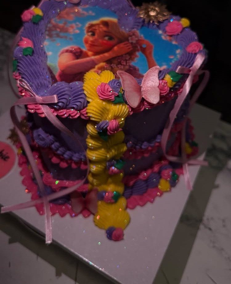 Purple Belle themed cake with pink ribbons, yellow icing, and a character image.