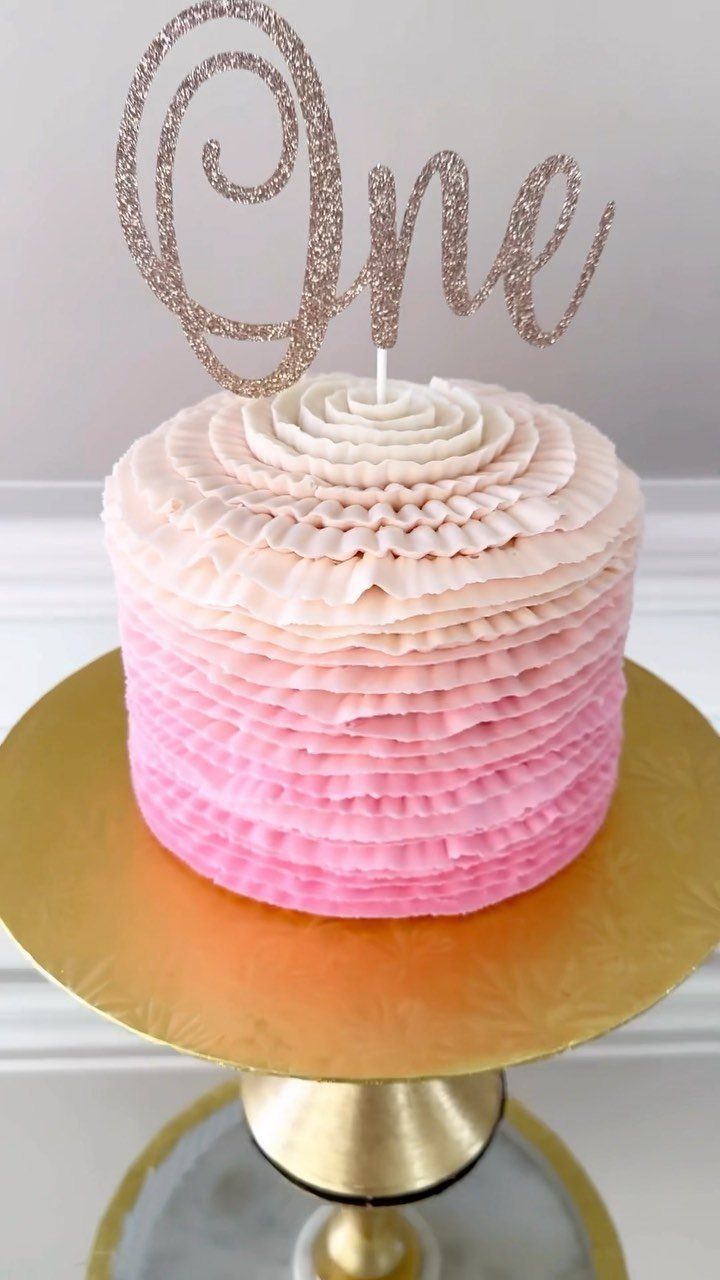 Pink ombre ruffled cake with a gold glittery One topper on gold stand