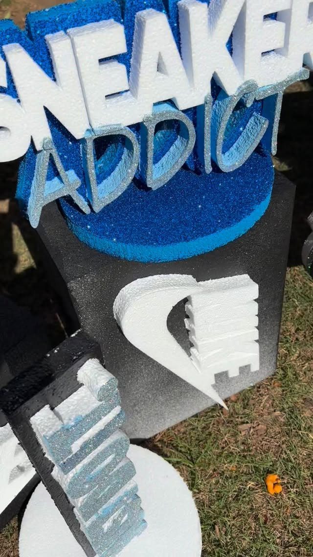 Large 3D foam letters spelling SNEAKER ADDICT on a blue and grey pedestal.