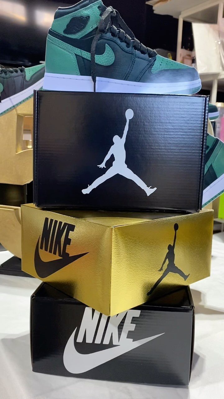 Stacked Nike and Jordan shoe boxes with a green sneaker on top.