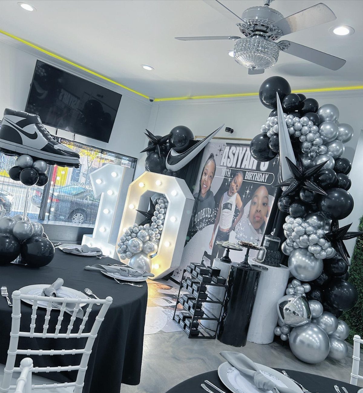 Party decor with black and silver balloons, glowing numbers, and sneaker accents.