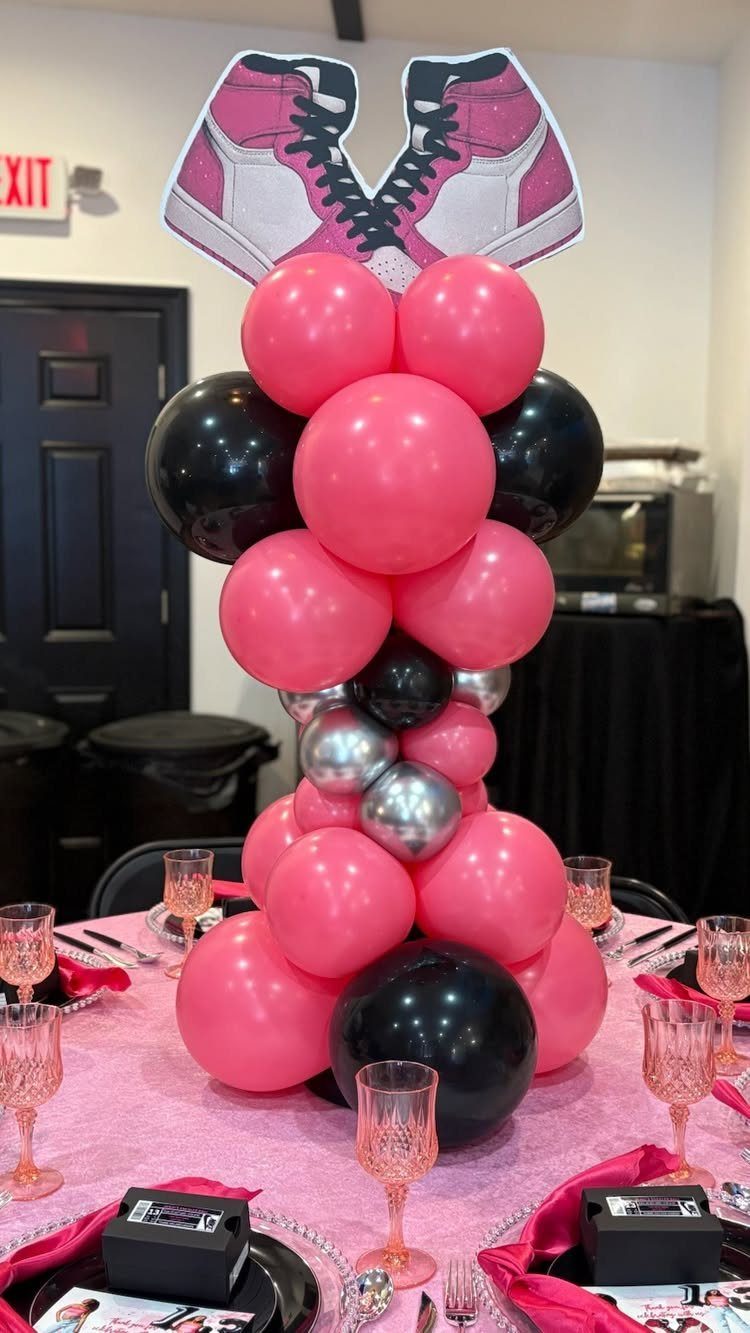 Balloon centerpiece with pink and black balloons topped with pink sneaker cutouts.