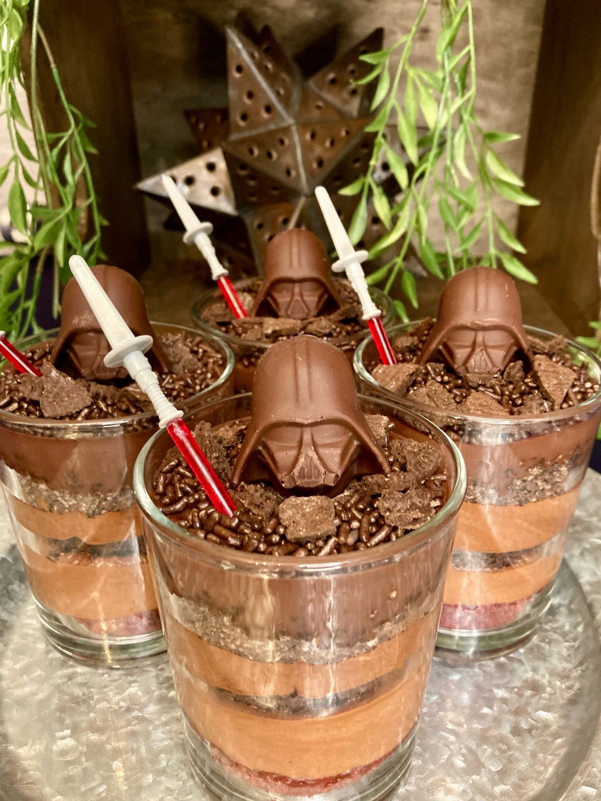 Chocolate mousse desserts topped with Darth Vader helmets and miniature lightsabers in glasses.