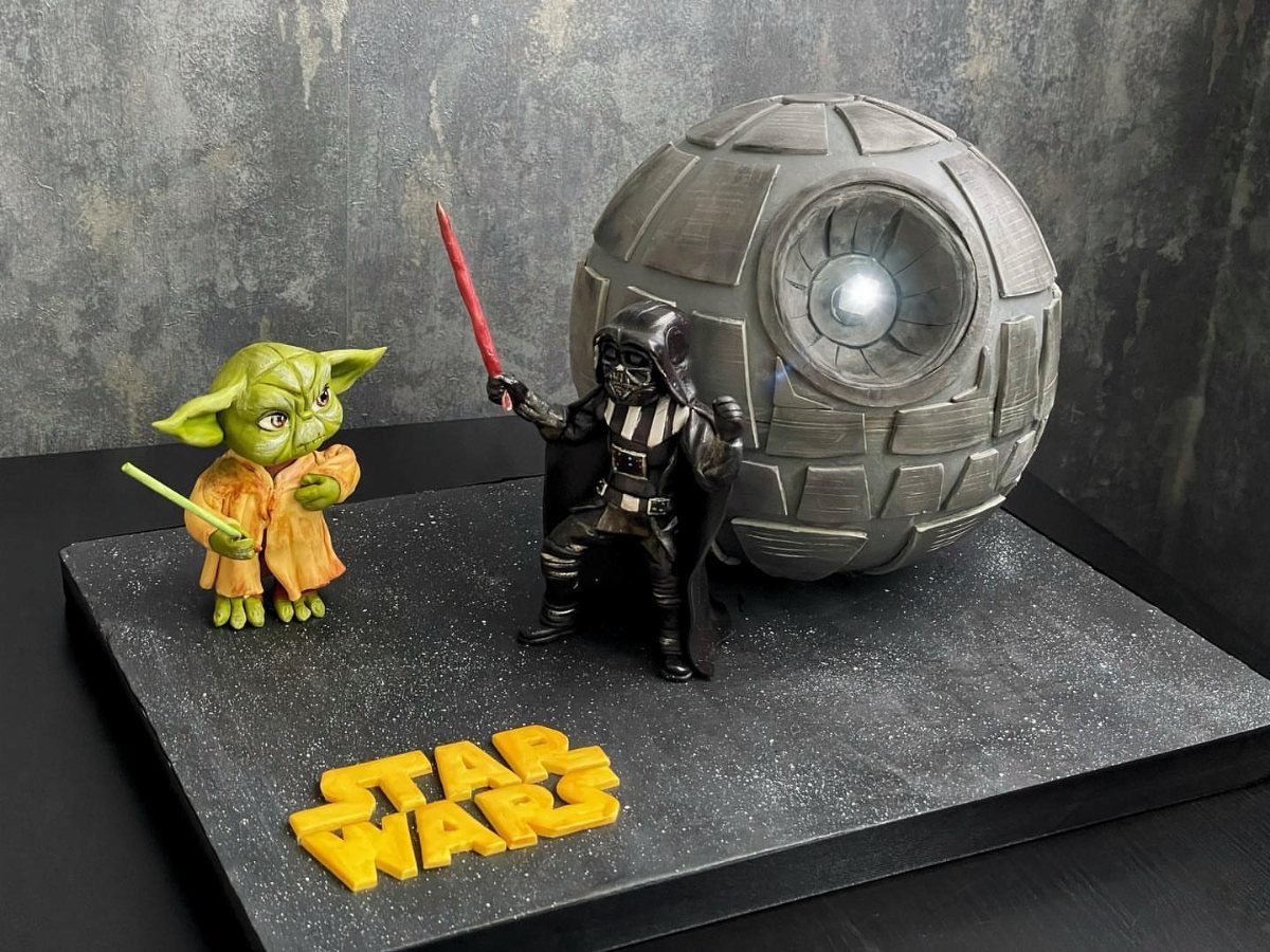 Death Star cake with edible Yoda and Darth Vader figures on starry board
