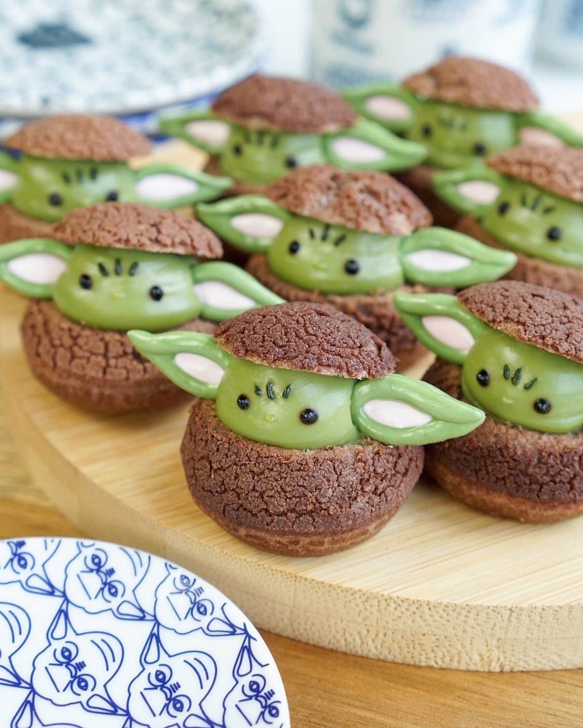 Grogu themed cream puffs with green frosting faces on a wooden board