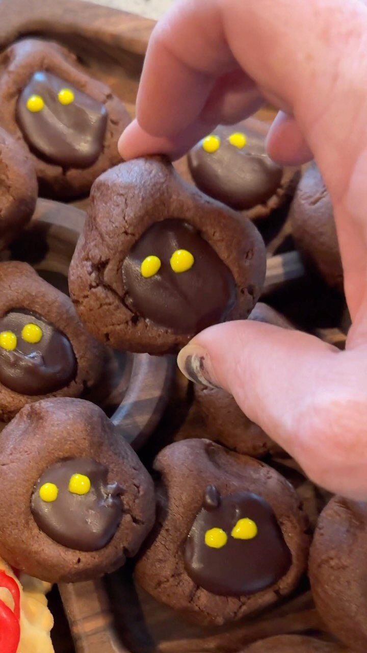 Chocolate cookies with chocolate centers and yellow candy eyes on a wooden platter