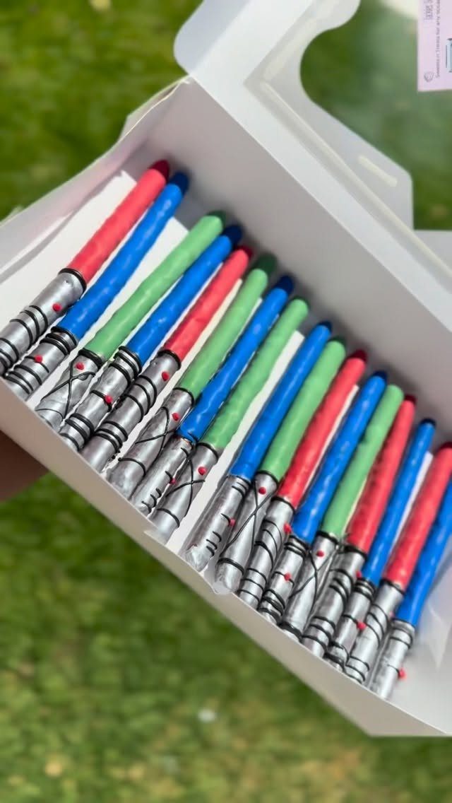 Lightsaber pretzel rods with red, blue, and green coatings in a white box.