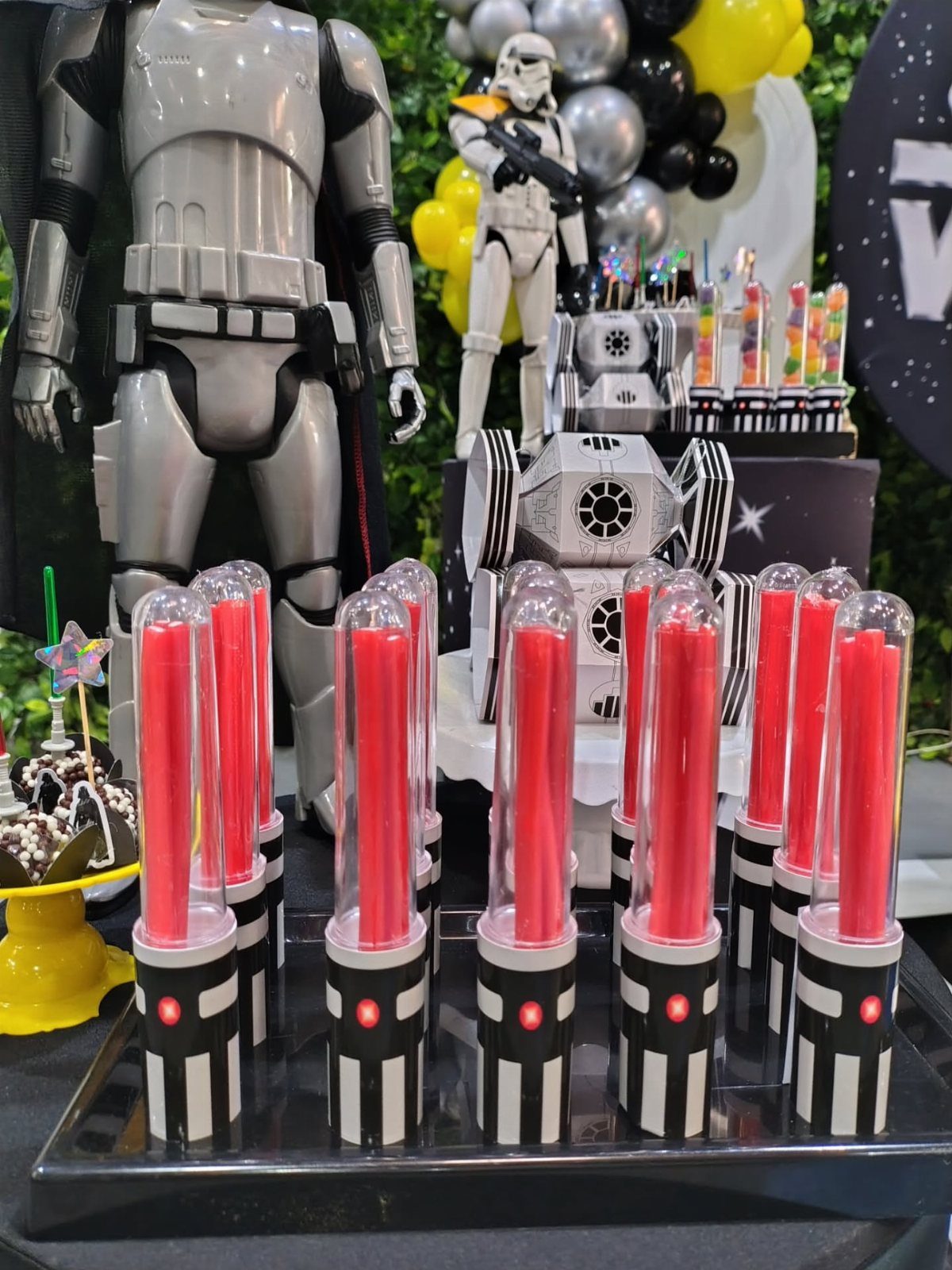 Red lightsaber party favors in striped holders at a Star Wars themed party.