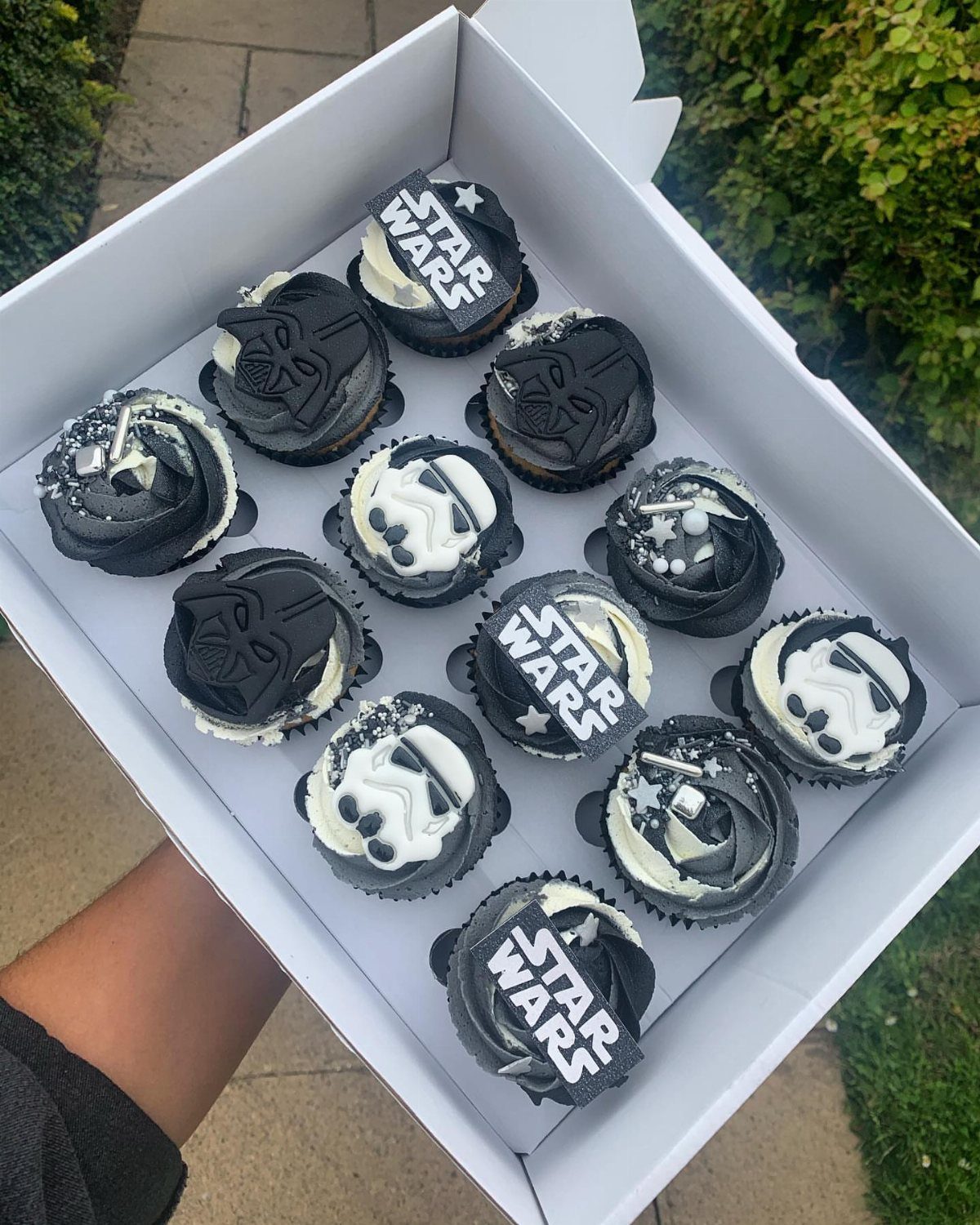 Star Wars themed cupcakes with Stormtrooper and Darth Vader designs in a white box