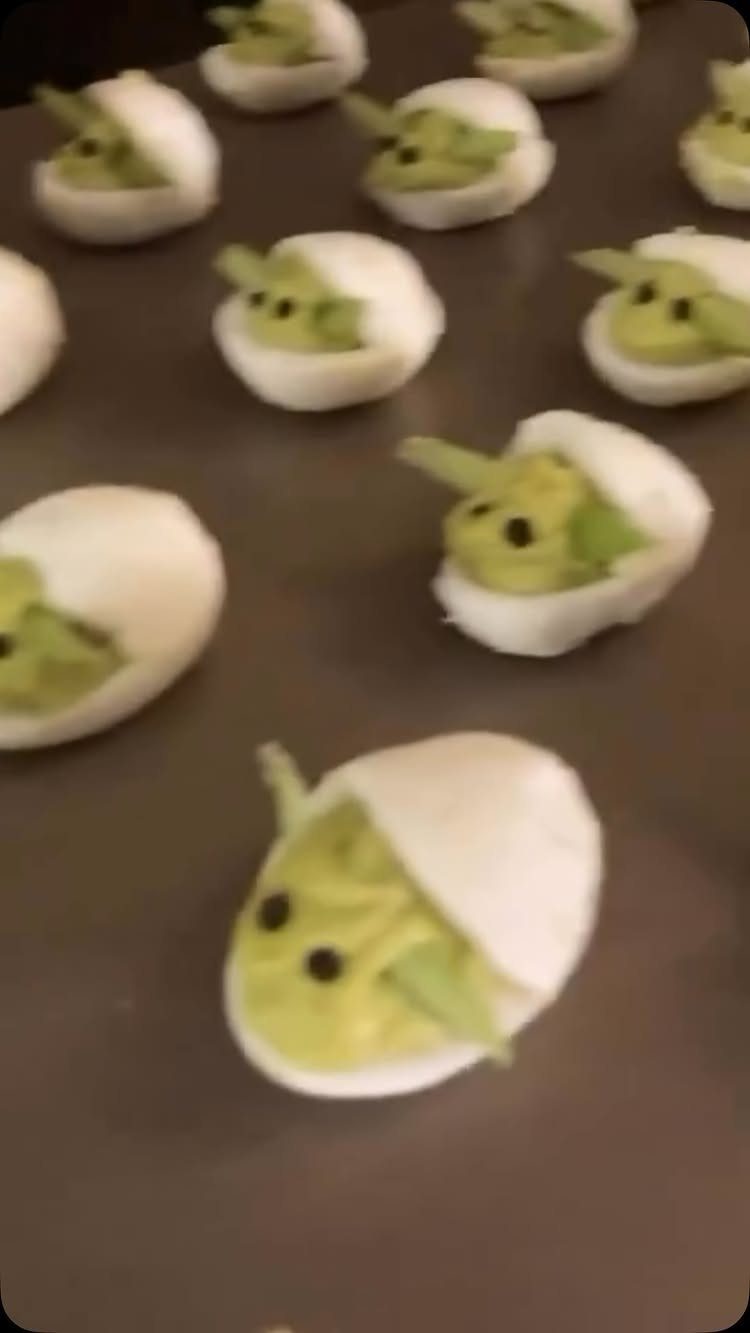 Yoda-shaped guacamole appetizers in white shells arranged on a brown platter