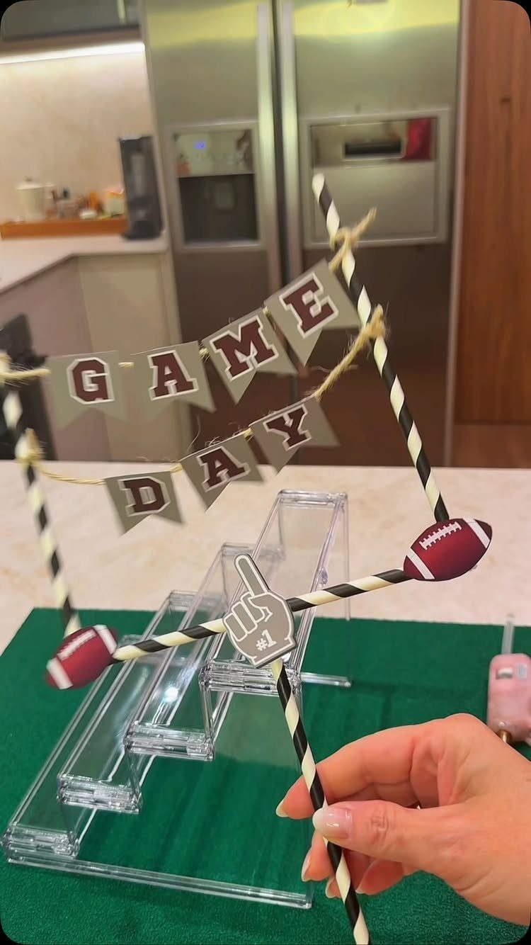 Football-themed game day banner decoration held by a hand over a green surface.