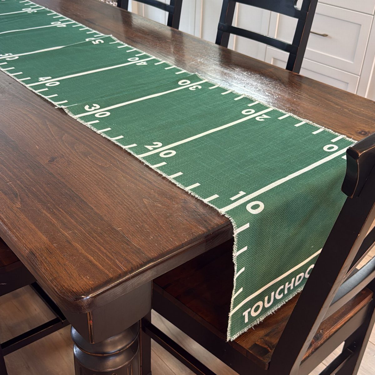 Green football field table runner with white yard lines on a wooden table.