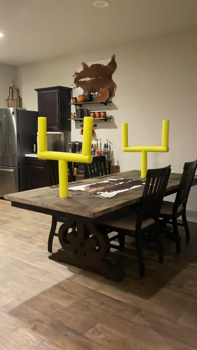 Yellow football goal post decorations on a rustic wooden dining table in a kitchen