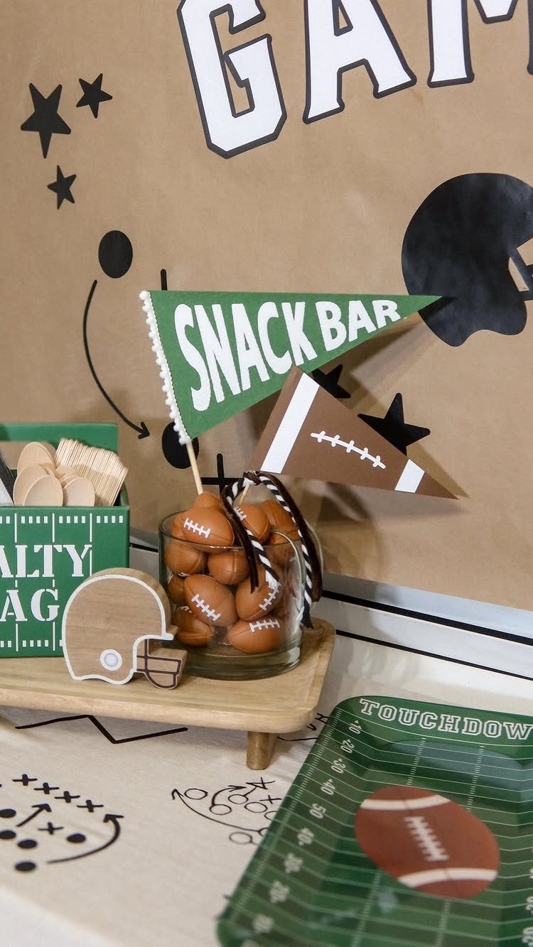 Football-themed snack table with football chocolates, a snack bar pennant, and themed tableware.