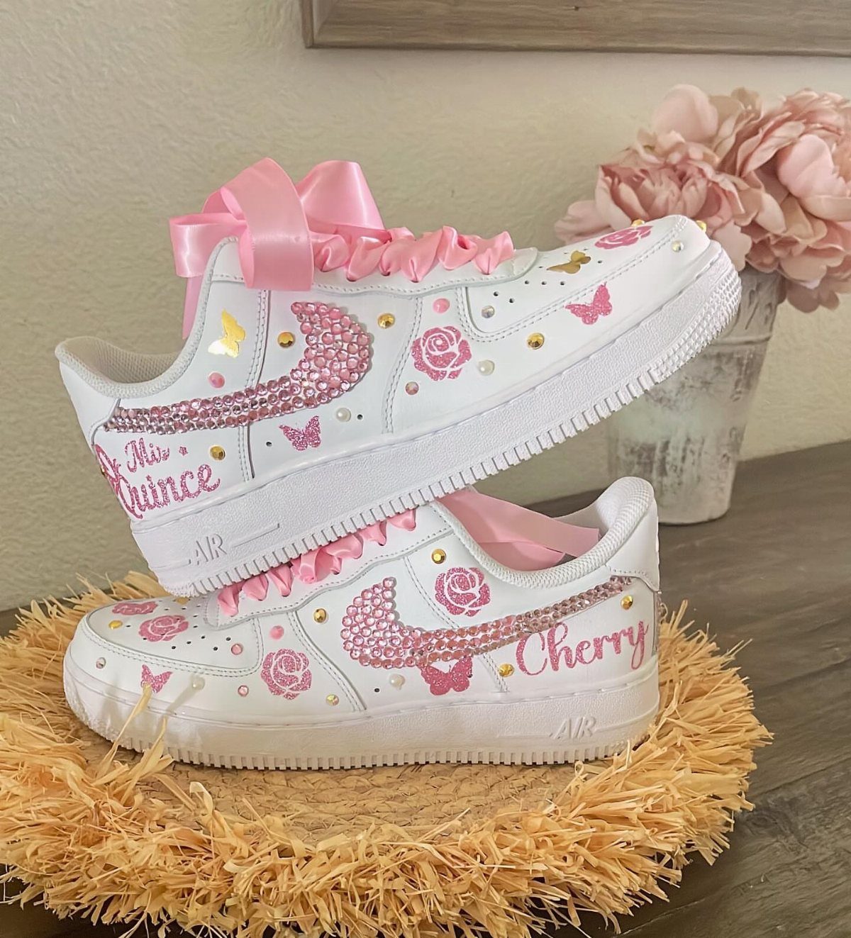 Custom white sneakers with pink rhinestones and ribbons on a straw mat