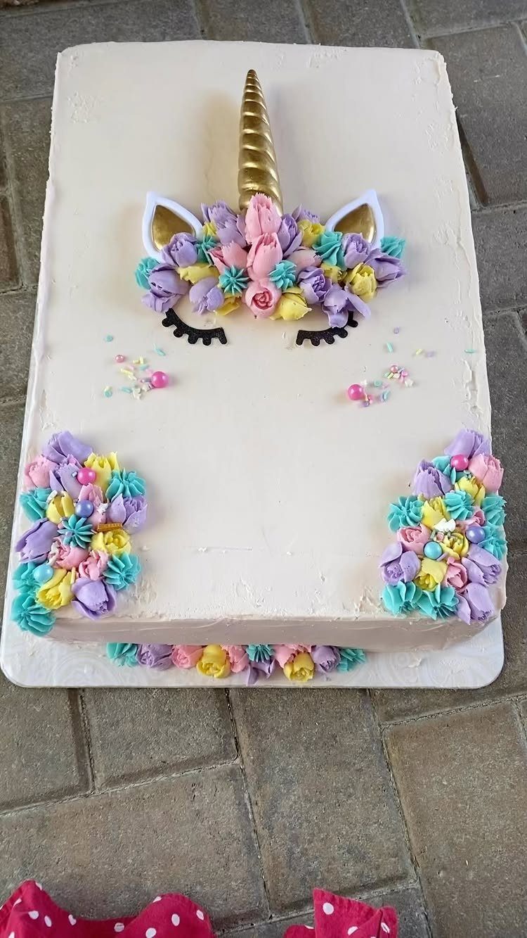 Rectangular white unicorn cake with gold horn and colorful buttercream floral decorations.