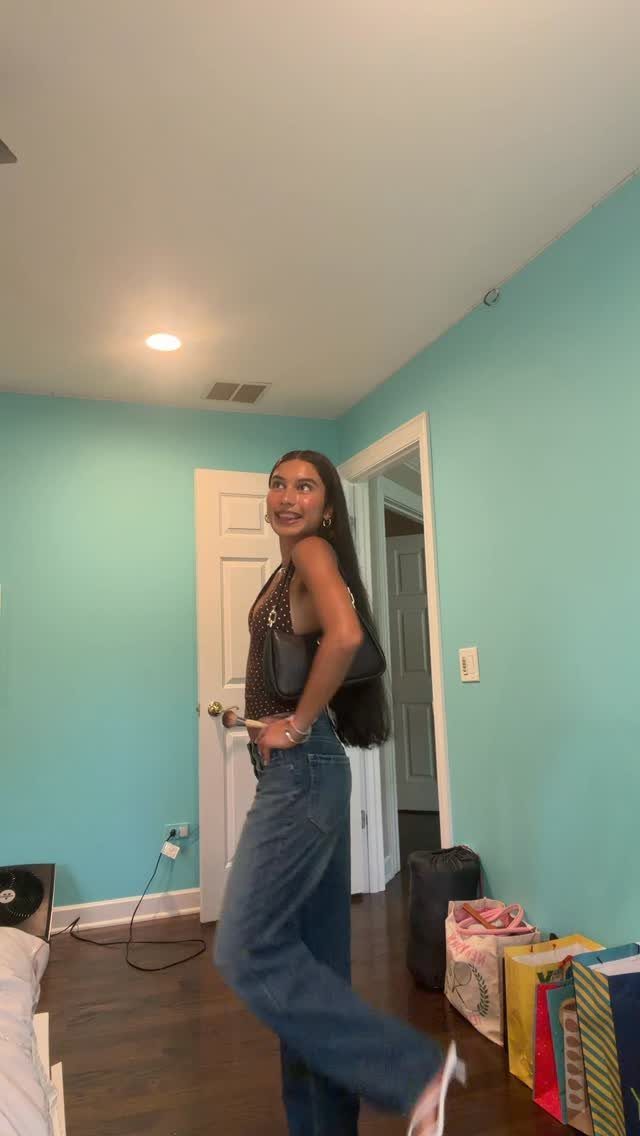 Young woman posing in a patterned top and blue jeans in a blue room
